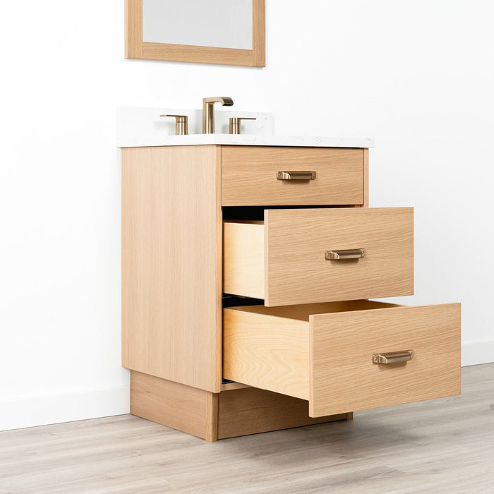 Ashbury 24" White Oak Vanity with Arctic Trace quartz top and new bronze handle – toe kick base, left-side open view.